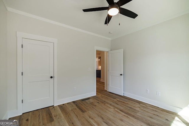 unfurnished bedroom with light wood-type flooring, ornamental molding, and ceiling fan