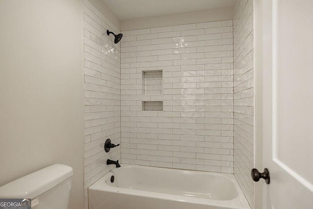 bathroom featuring tiled shower / bath combo and toilet