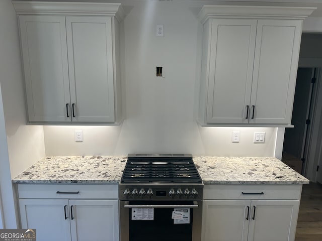 kitchen with light stone counters, white cabinetry, range with gas cooktop, and hardwood / wood-style flooring