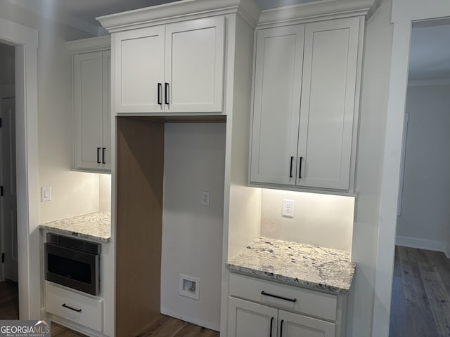 kitchen with light stone counters, built in microwave, dark hardwood / wood-style floors, and white cabinets