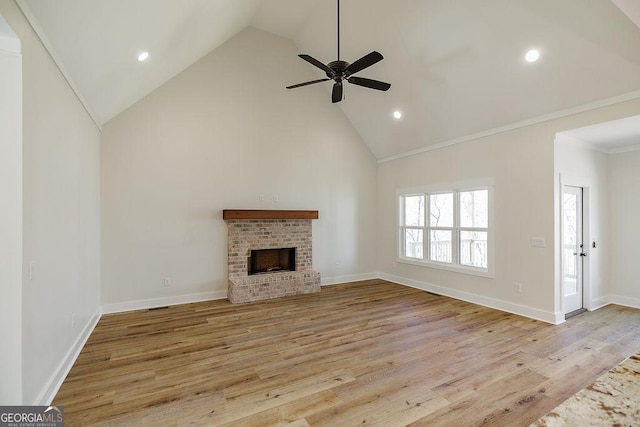 unfurnished living room featuring light hardwood / wood-style floors, ceiling fan, a fireplace, high vaulted ceiling, and ornamental molding