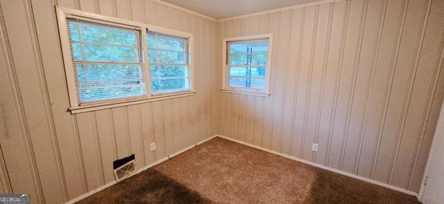 unfurnished room with ornamental molding, carpet floors, and wooden walls