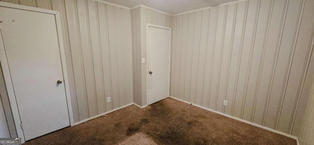 unfurnished bedroom with wood walls, ornamental molding, and carpet