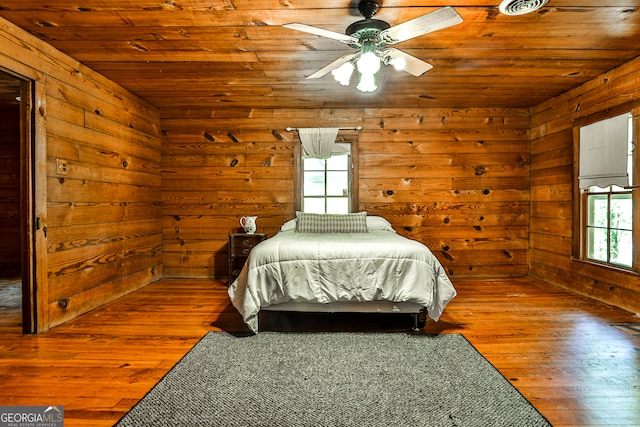 bedroom featuring wood ceiling, hardwood / wood-style floors, wood walls, and ceiling fan