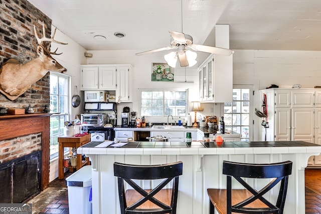 kitchen with tile countertops, a kitchen breakfast bar, and white cabinets