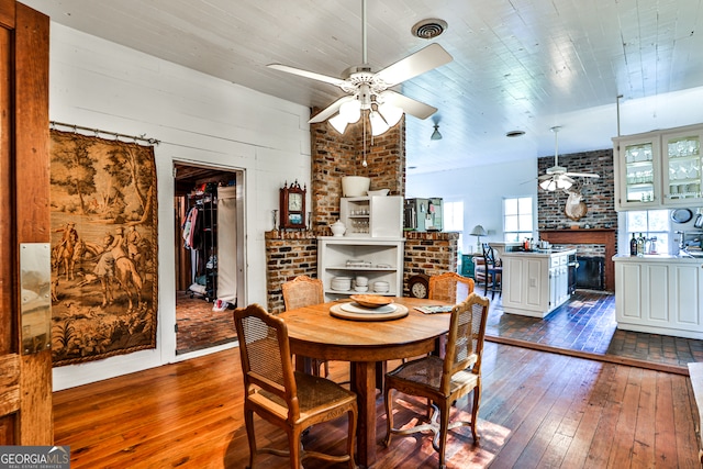 dining room featuring brick wall, ceiling fan, and dark hardwood / wood-style flooring