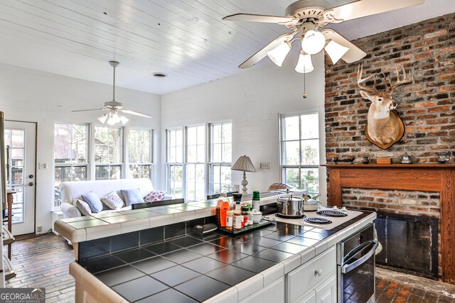 164 Manning Gin Rd, Bethlehem, GA 30620 - kitchen with tile counters, brick flooring, oven, ceiling fan, and a fireplace