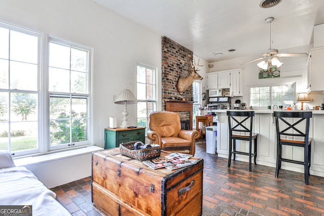 living room with a brick fireplace, a healthy amount of sunlight, and ceiling fan