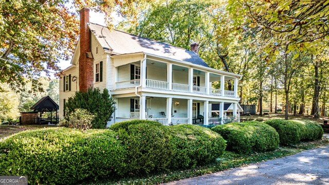 164 Manning Gin Rd, Bethlehem, GA 30620 - view of front of house with a balcony, a chimney, covered porch, and a ceiling fan