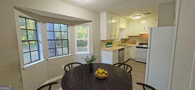 kitchen featuring white appliances, sink, a textured ceiling, white cabinetry, and light hardwood / wood-style floors