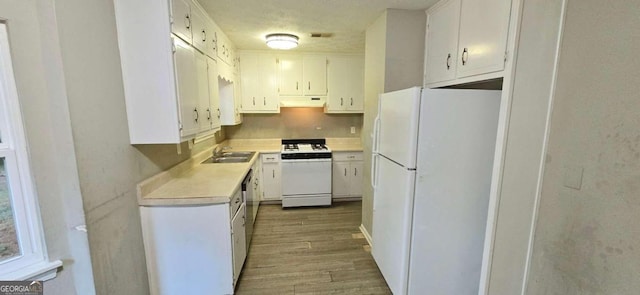 kitchen with white cabinets, a sink, light countertops, light wood-type flooring, and white appliances