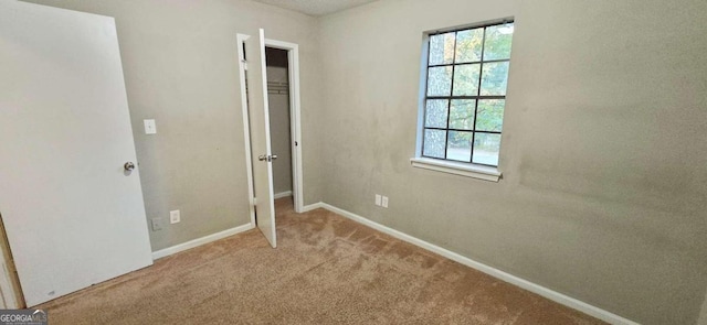 unfurnished bedroom with carpet, a closet, and baseboards