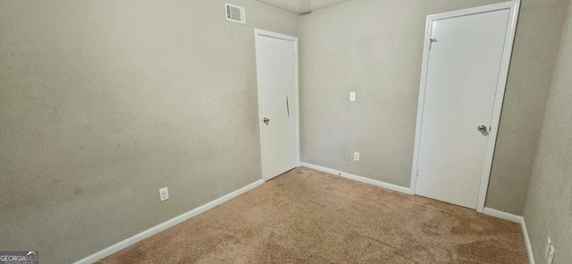 unfurnished bedroom with baseboards, visible vents, and carpet