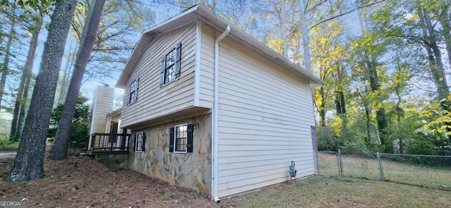 view of property exterior featuring fence and stone siding
