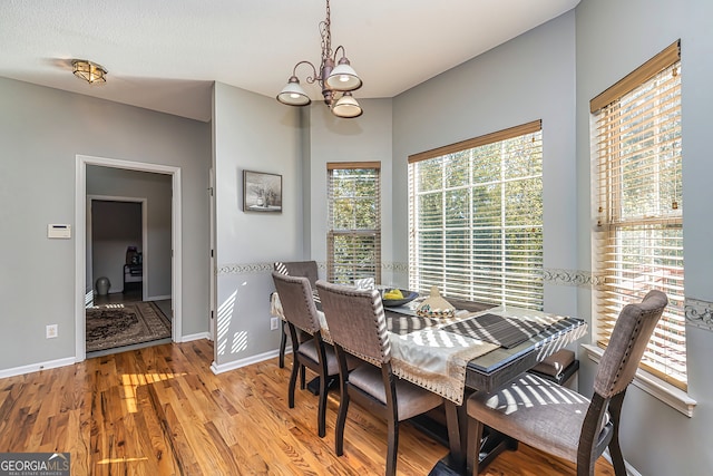 dining room with a wealth of natural light, an inviting chandelier, and light hardwood / wood-style floors