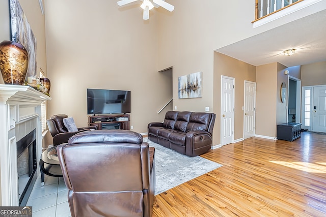 living room with a towering ceiling, light hardwood / wood-style floors, and ceiling fan