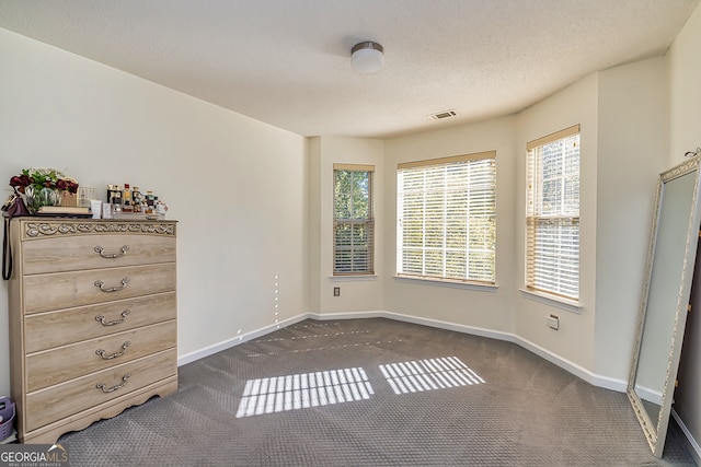 unfurnished bedroom featuring a textured ceiling and dark carpet