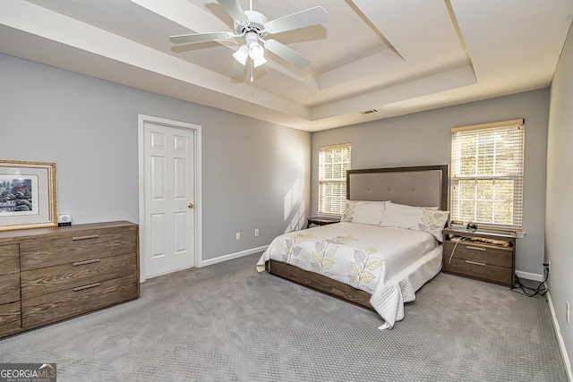 bedroom featuring light colored carpet, a raised ceiling, and ceiling fan