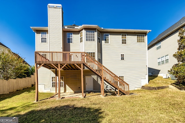 rear view of house featuring a wooden deck and a lawn