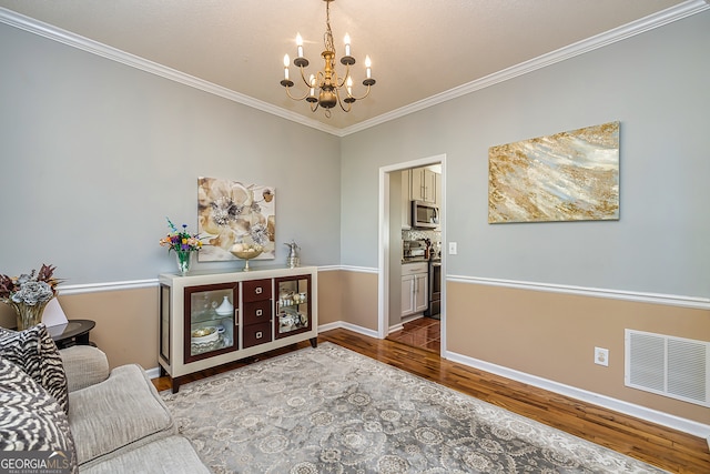 interior space featuring ornamental molding, wood-type flooring, and an inviting chandelier