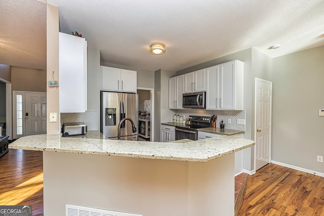 kitchen featuring light wood-type flooring, stainless steel appliances, kitchen peninsula, and white cabinets