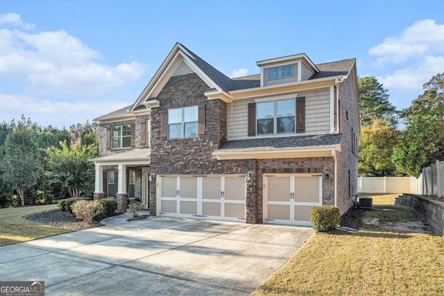 craftsman house with a front lawn, central AC unit, and a garage