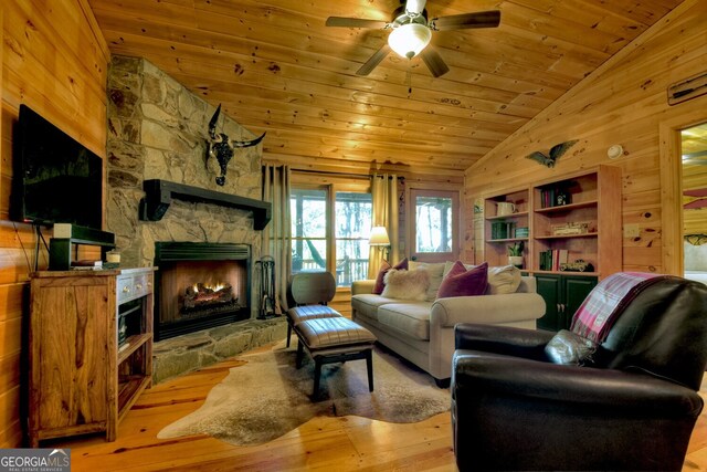 living room with wooden ceiling, high vaulted ceiling, a stone fireplace, built in shelves, and light wood-type flooring