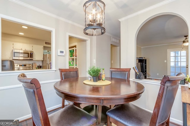 dining room with a notable chandelier, ornamental molding, and hardwood / wood-style floors