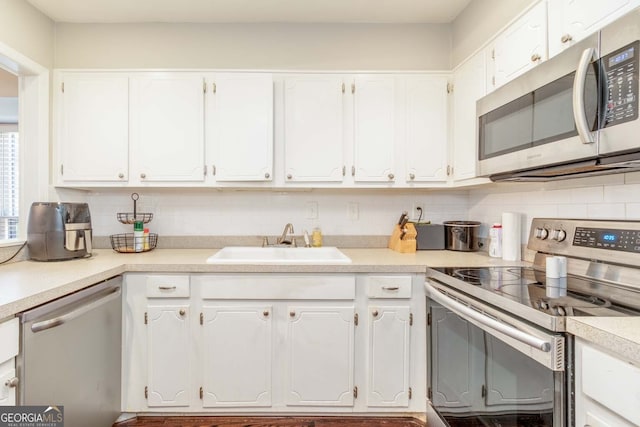 kitchen featuring white cabinetry, stainless steel appliances, tasteful backsplash, and sink