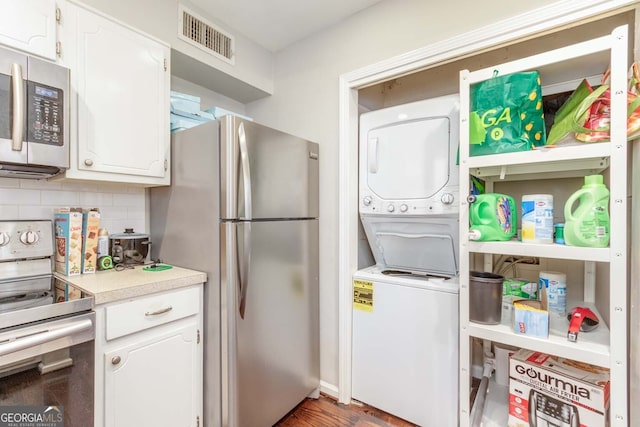 kitchen with stacked washer and dryer, white cabinetry, tasteful backsplash, and stainless steel appliances