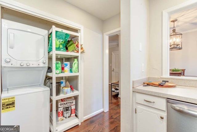 laundry room with an inviting chandelier, stacked washer and dryer, crown molding, and dark hardwood / wood-style flooring