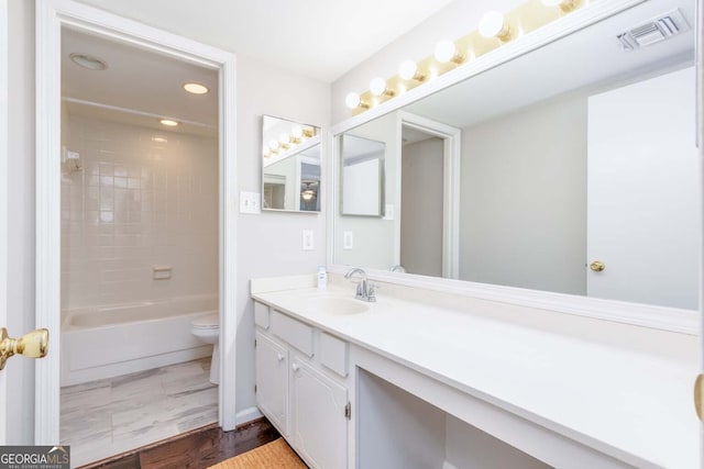 full bathroom featuring toilet, tiled shower / bath, vanity, and wood-type flooring