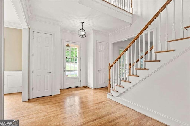 entryway featuring light hardwood / wood-style floors, ornamental molding, and an inviting chandelier