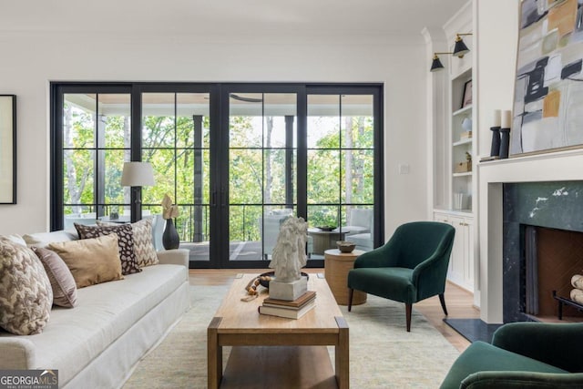 living room featuring crown molding, a fireplace, hardwood / wood-style floors, and built in features