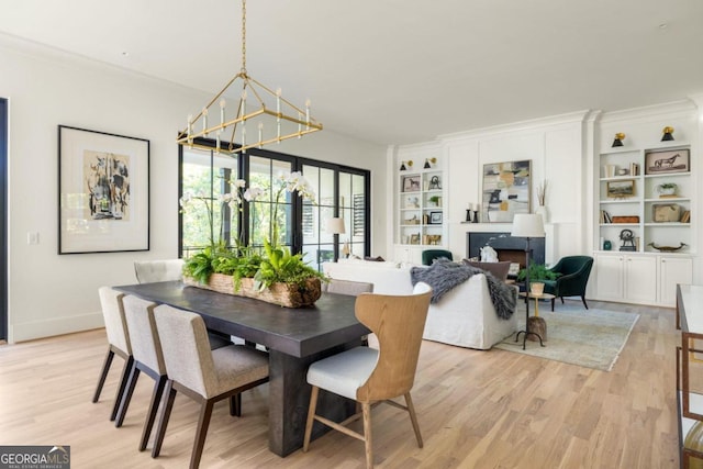 dining room featuring an inviting chandelier, ornamental molding, built in features, and light hardwood / wood-style floors