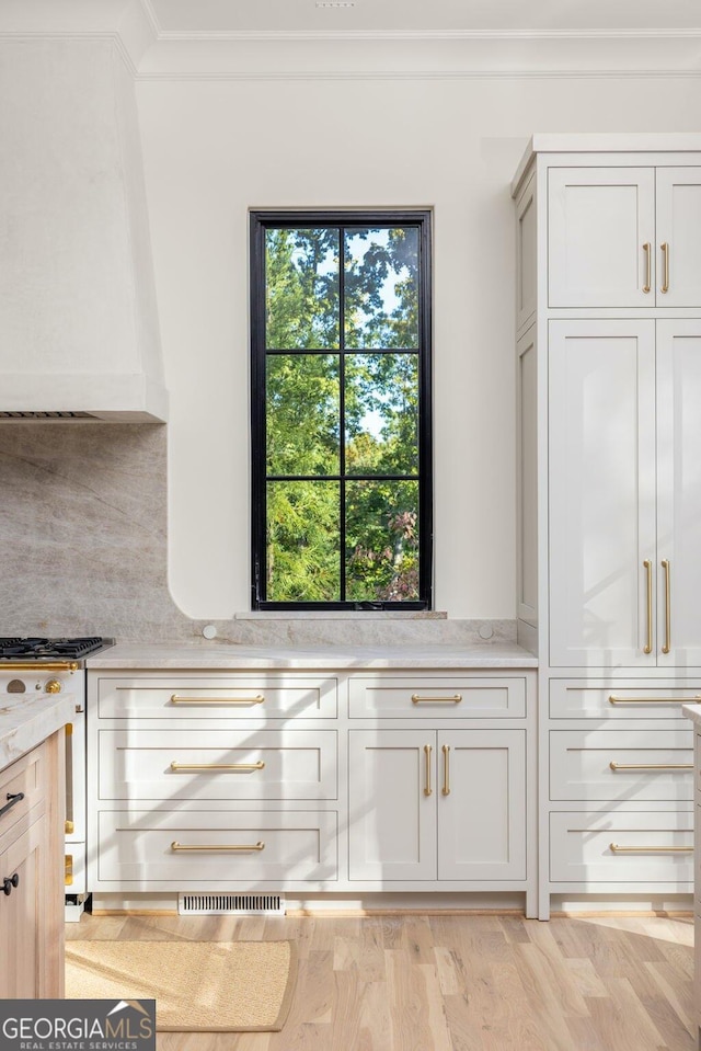 kitchen featuring light stone countertops, light wood-type flooring, and decorative backsplash