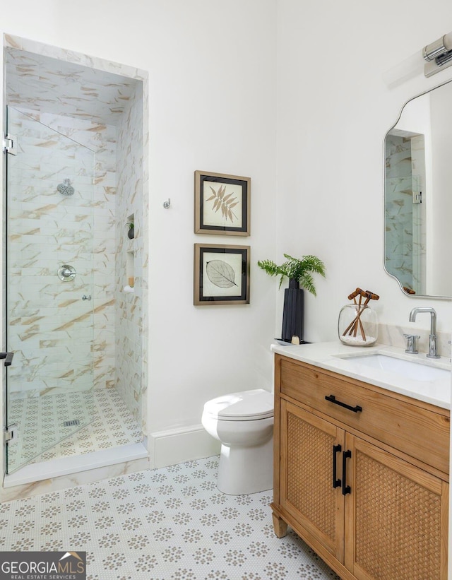 bathroom featuring tile patterned floors, vanity, toilet, and a tile shower