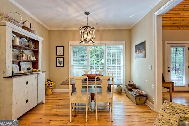 dining space with a notable chandelier, light wood-type flooring, and crown molding