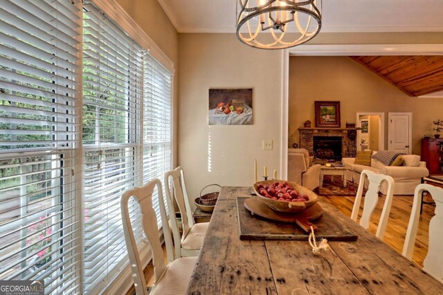 dining room with lofted ceiling with beams, hardwood / wood-style floors, wooden ceiling, crown molding, and a chandelier