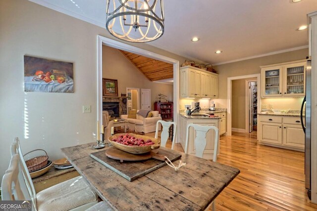 dining room with lofted ceiling, a chandelier, light hardwood / wood-style flooring, and crown molding