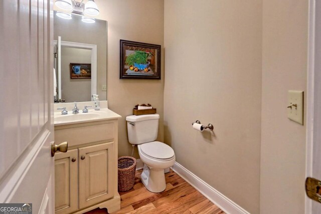 bathroom with toilet, hardwood / wood-style floors, and vanity