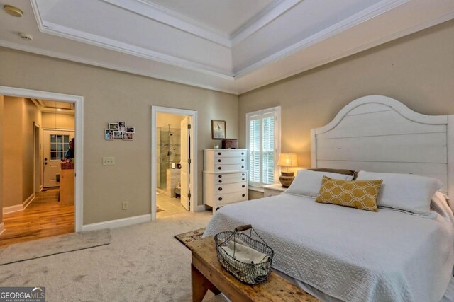 bedroom with connected bathroom, crown molding, light carpet, and a tray ceiling