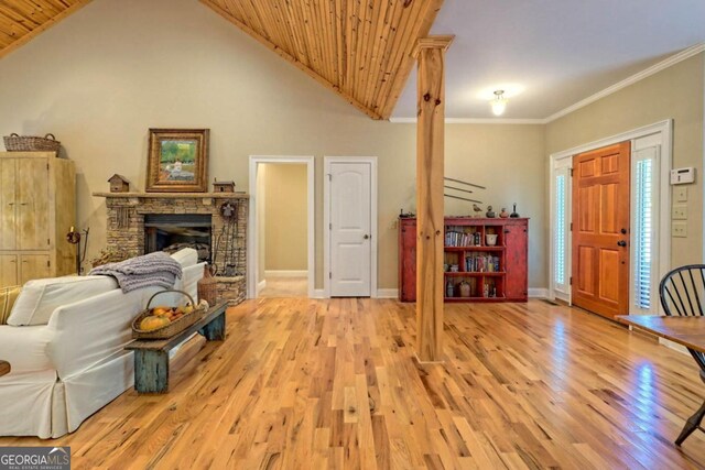 living room featuring high vaulted ceiling, wooden ceiling, light hardwood / wood-style flooring, ornamental molding, and a fireplace