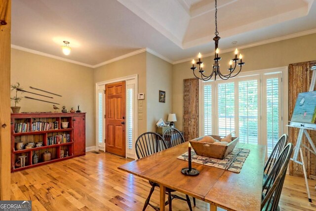 dining space with a notable chandelier, ornamental molding, hardwood / wood-style flooring, and a tray ceiling