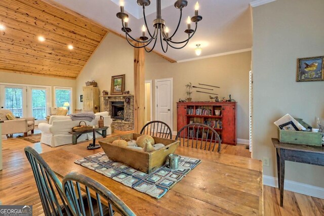 dining space with light hardwood / wood-style floors, wooden ceiling, crown molding, an inviting chandelier, and high vaulted ceiling