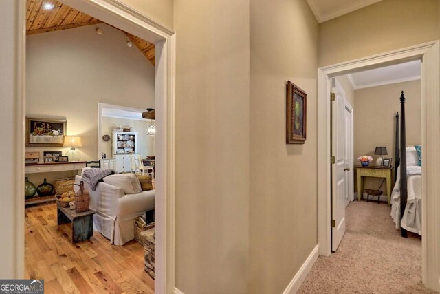 corridor featuring light hardwood / wood-style flooring, ornamental molding, high vaulted ceiling, and wooden ceiling