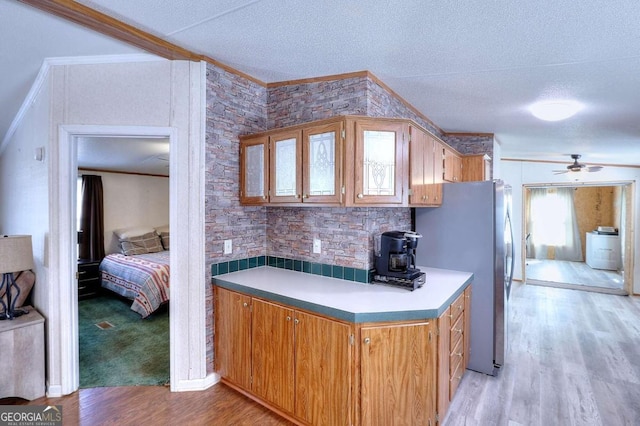 kitchen with washer / clothes dryer, crown molding, light hardwood / wood-style flooring, and stainless steel refrigerator