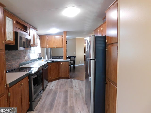 kitchen with sink, backsplash, light hardwood / wood-style floors, and appliances with stainless steel finishes