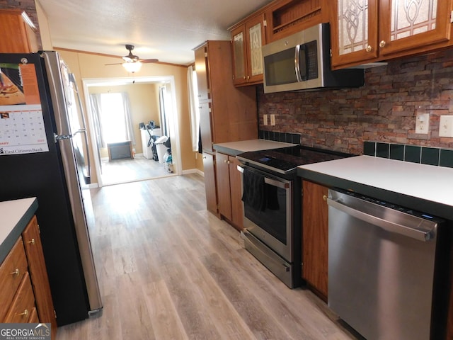 kitchen with ceiling fan, appliances with stainless steel finishes, light hardwood / wood-style floors, and backsplash