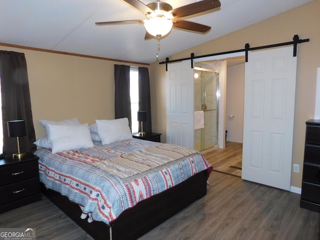 bedroom with crown molding, ceiling fan, dark hardwood / wood-style floors, vaulted ceiling, and a barn door